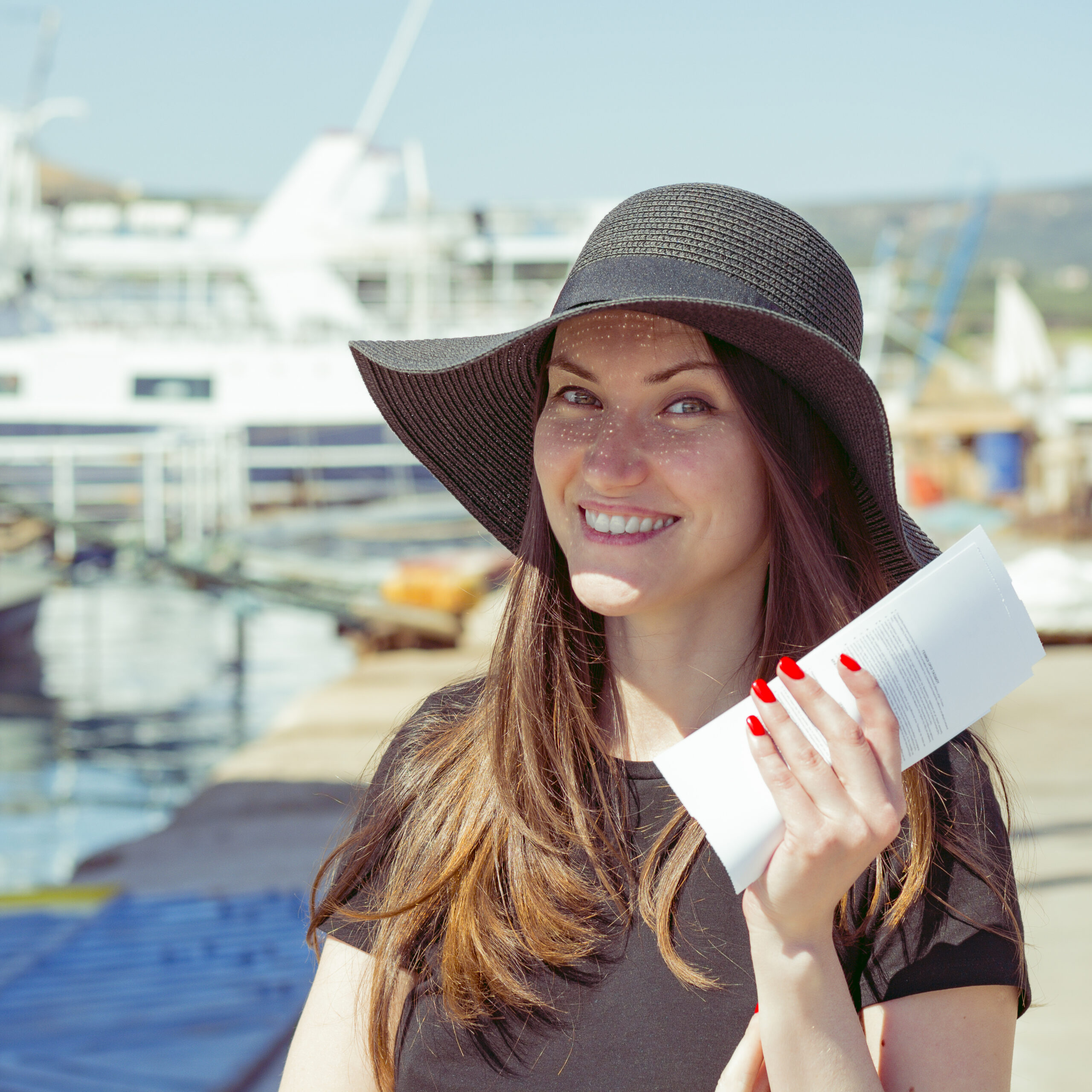 Travel deals concept. Happy smiling woman with tickets for the cruise at the port resort city. journey through water. Rest time at sea.